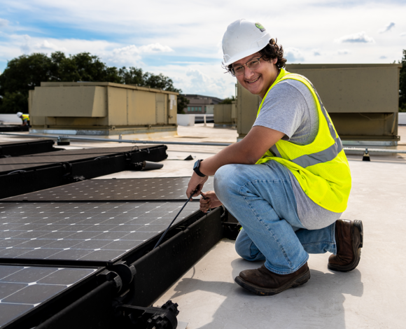 student working on solar panels on top of a building